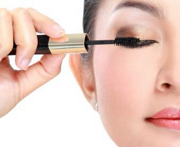 woman applying mascara to her eyeashes