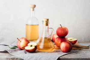 bottles of Apple cider vinegar and fresh red apples.