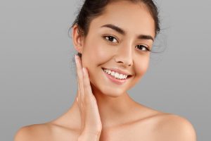 Beautiful Face of young woman with perfect skin. Grey background