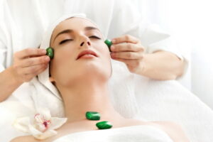Young Beautiful Woman Having Facial Massage with Stones .