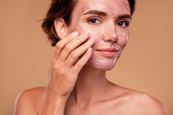 Woman applying a glittering, translucent face mask during a relaxing facial skincare treatment.