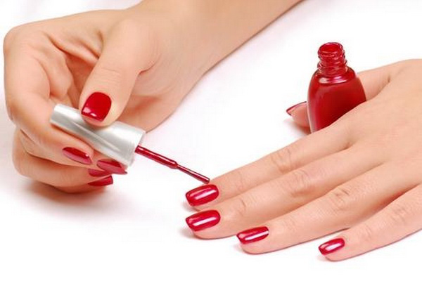 woman painting her fingernails with red nail polish