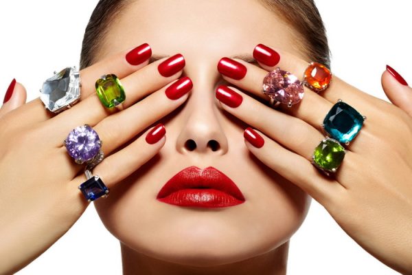 women covering her eyes with hands painted with red nail polish