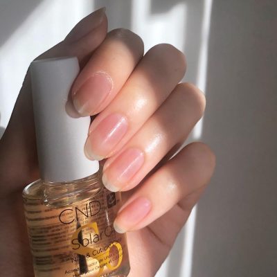 woman's hands holding a bottle of cnd solar oil