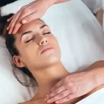 A practitioner performing a calming Reiki energy healing treatment on a client